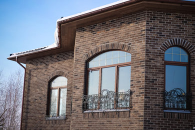 Foto de fachada de casa marrón clásica grande de dos plantas con revestimiento de ladrillo, tejado a cuatro aguas y tejado de teja de barro