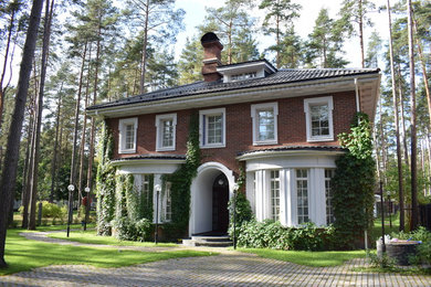 Imagen de fachada de casa roja clásica de tamaño medio de dos plantas con revestimiento de ladrillo y tejado de teja de barro