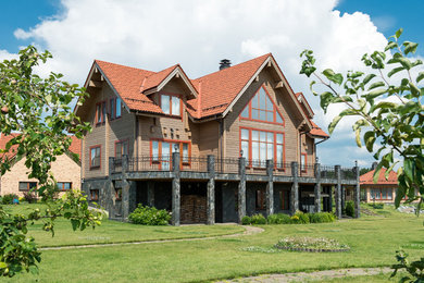 На фото: частный загородный дом в стиле кантри с двускатной крышей и черепичной крышей