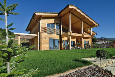 Modelo de fachada de casa marrón grande de dos plantas con revestimiento de madera y tejado a dos aguas