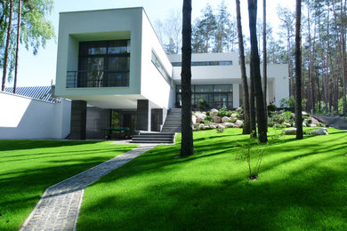 Diseño de fachada de casa blanca actual de tamaño medio de dos plantas con revestimientos combinados y tejado plano