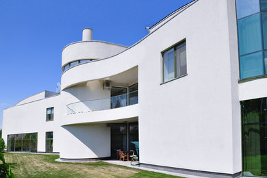 На фото: двухэтажный, белый частный загородный дом среднего размера в современном стиле с облицовкой из бетона и плоской крышей с
