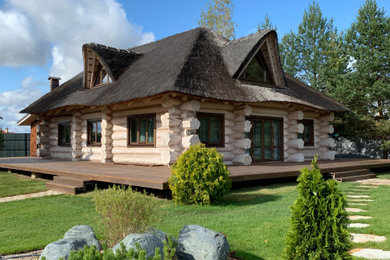 Идея дизайна: большой, двухэтажный, деревянный, бежевый дом из бревен в стиле рустика с зеленой крышей и полувальмовой крышей