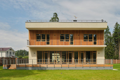 На фото: большой, двухэтажный, бежевый частный загородный дом в стиле модернизм с облицовкой из цементной штукатурки, плоской крышей и крышей из смешанных материалов