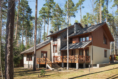 Ejemplo de fachada de casa marrón rústica de tres plantas con tejado a dos aguas, revestimientos combinados y tejado de teja de madera