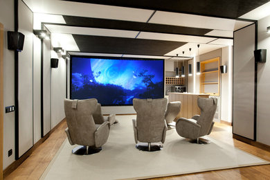 Foto de cine en casa cerrado actual con paredes blancas, suelo de madera en tonos medios y pantalla de proyección