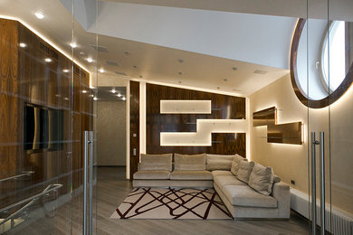 Diseño de cine en casa abierto actual de tamaño medio con paredes beige, suelo de madera pintada, televisor colgado en la pared y suelo gris