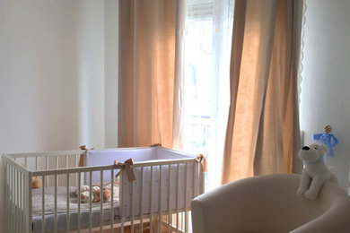 Imagen de habitación de bebé neutra clásica renovada pequeña con paredes blancas, suelo de madera en tonos medios y suelo beige