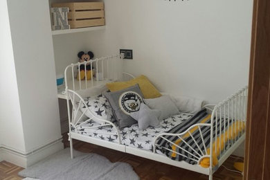 Esempio di una piccola cameretta per bambini da 1 a 3 anni scandinava con pareti bianche e pavimento in legno massello medio