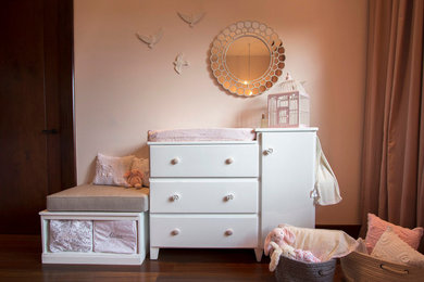 Modelo de dormitorio infantil de 1 a 3 años romántico pequeño con paredes rosas y suelo de madera en tonos medios