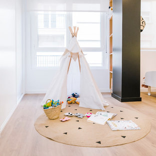 Imagen de dormitorio infantil de 1 a 3 años, nórdico, de tamaño medio, con paredes blancas, suelo de madera en tonos medios y suelo marrón
