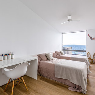 Imagen de dormitorio infantil marinero con paredes blancas, suelo de madera en tonos medios y suelo marrón