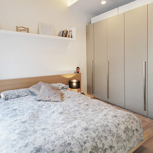 Modelo de habitación de invitados mediterránea con paredes blancas, suelo de madera en tonos medios y suelo beige