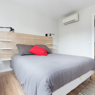 Modelo de dormitorio contemporáneo, de tamaño medio, con paredes grises, suelo de madera clara y suelo beige