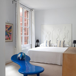 Diseño de dormitorio bohemio con paredes blancas, suelo de madera en tonos medios y suelo marrón