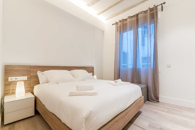 Cette image montre une chambre parentale minimaliste de taille moyenne avec un mur blanc, un sol en bois brun et aucune cheminée.