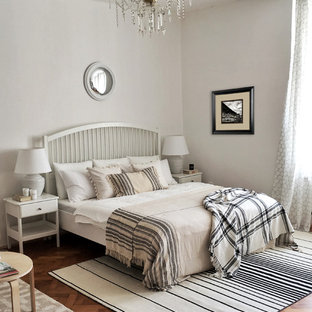 Cette photo montre une chambre mansardée ou avec mezzanine scandinave de taille moyenne avec un mur blanc, un sol en bois brun et un sol marron.