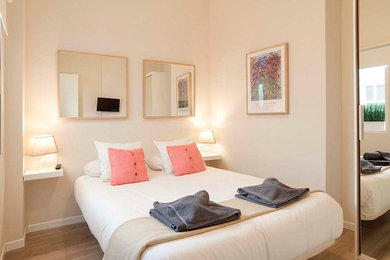 Imagen de dormitorio principal escandinavo de tamaño medio sin chimenea con paredes blancas y suelo de madera en tonos medios