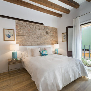 Diseño de dormitorio mediterráneo con paredes blancas, suelo de madera en tonos medios y suelo marrón