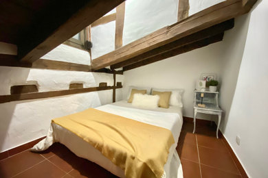 Diseño de dormitorio principal ecléctico pequeño con paredes blancas, suelo de baldosas de cerámica y suelo marrón