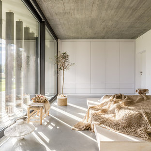 Modelo de dormitorio moderno con paredes blancas, suelo de cemento y suelo gris