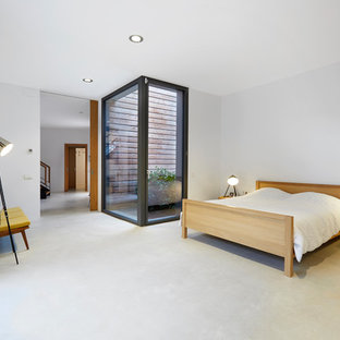 Modelo de dormitorio principal, actual, con paredes blancas, suelo de cemento y suelo gris