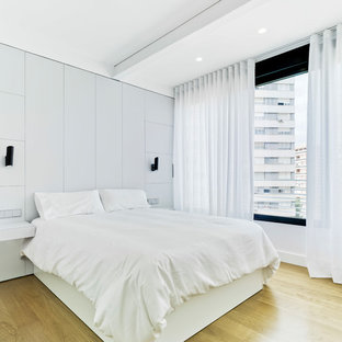 Modelo de dormitorio principal, contemporáneo, con paredes blancas, suelo de madera clara y suelo beige