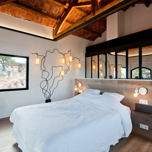 Diseño de dormitorio principal, mediterráneo, de tamaño medio, sin chimenea, con paredes blancas, suelo de madera en tonos medios y suelo marrón