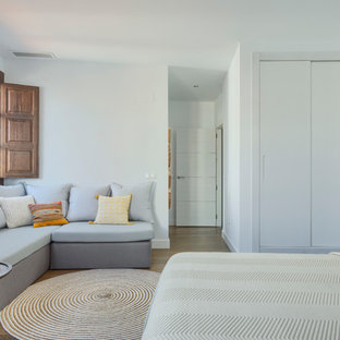 Diseño de habitación de invitados actual, grande, con paredes blancas, suelo de madera en tonos medios y suelo marrón