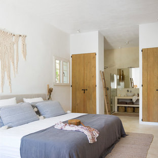 Imagen de dormitorio mediterráneo con paredes blancas y suelo beige
