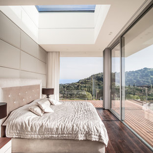 Foto de dormitorio principal, minimalista, con suelo de madera oscura, paredes blancas y suelo marrón