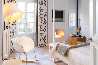 Diseño de dormitorio principal escandinavo de tamaño medio con paredes blancas, suelo de madera clara y todas las chimeneas