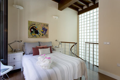 Ejemplo de dormitorio tipo loft clásico renovado de tamaño medio sin chimenea con paredes beige y suelo de madera en tonos medios