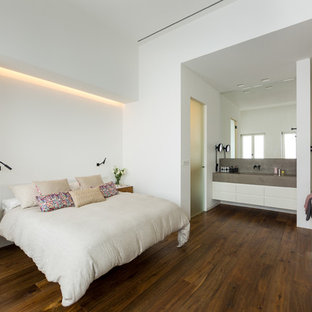 Modelo de dormitorio principal, contemporáneo, con paredes blancas, suelo marrón y suelo de madera en tonos medios