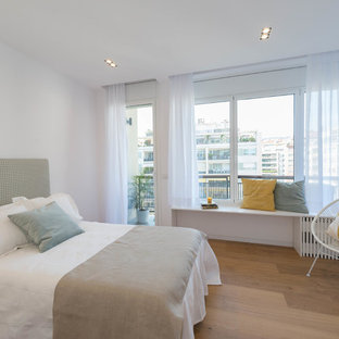 Modelo de habitación de invitados contemporánea con paredes blancas y suelo de madera en tonos medios