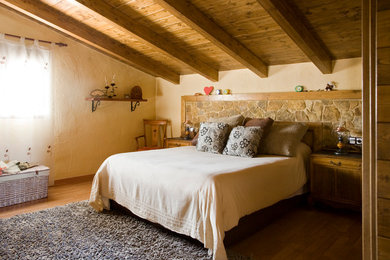 Ejemplo de dormitorio principal rústico de tamaño medio sin chimenea con paredes beige y suelo de madera en tonos medios