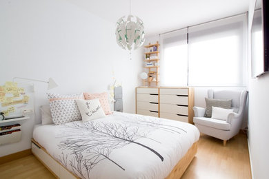 Imagen de dormitorio nórdico de tamaño medio con paredes blancas, suelo de madera en tonos medios y suelo marrón