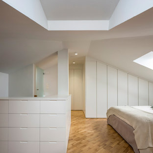 Foto de dormitorio actual con paredes blancas, suelo de madera clara y suelo marrón