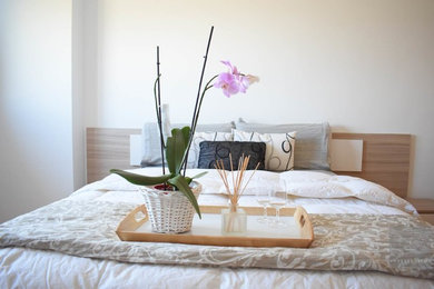 Modelo de dormitorio principal moderno de tamaño medio con paredes blancas, suelo de madera clara y suelo beige