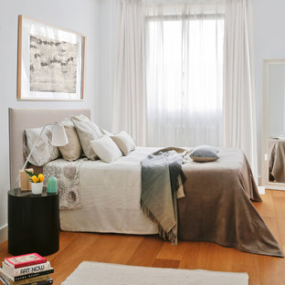 Kleines Modernes Hauptschlafzimmer ohne Kamin mit weißer Wandfarbe, braunem Holzboden und orangem Boden in Madrid
