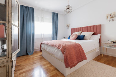 Ejemplo de dormitorio principal bohemio de tamaño medio con paredes blancas, suelo de madera en tonos medios y suelo marrón