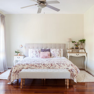 Imagen de dormitorio romántico con paredes beige, suelo de madera en tonos medios y suelo marrón