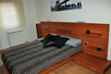Imagen de dormitorio principal tradicional renovado pequeño sin chimenea con paredes blancas y suelo de madera en tonos medios