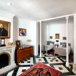 Ejemplo de dormitorio mediterráneo con paredes blancas, chimenea tradicional y suelo multicolor