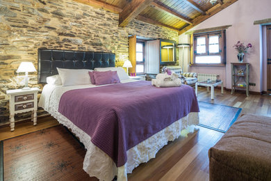 Diseño de dormitorio principal rural grande sin chimenea con suelo de madera en tonos medios