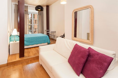 Modelo de dormitorio tipo loft minimalista de tamaño medio sin chimenea con paredes blancas y suelo de madera en tonos medios