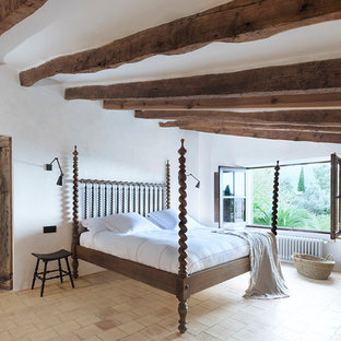 Ejemplo de dormitorio principal, mediterráneo, con paredes blancas, chimenea de esquina, marco de chimenea de yeso y suelo beige
