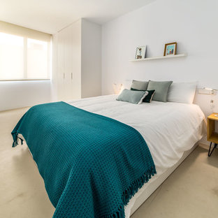 Modelo de habitación de invitados mediterránea con paredes blancas, suelo de cemento y suelo beige