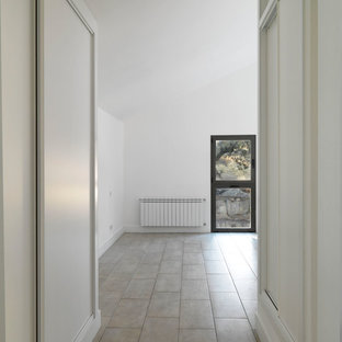 Modelo de dormitorio principal, de estilo de casa de campo, de tamaño medio, con paredes blancas, suelo de piedra caliza y suelo gris