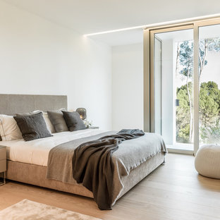 Diseño de dormitorio principal, actual, de tamaño medio, sin chimenea, con paredes blancas, suelo de madera en tonos medios y suelo marrón